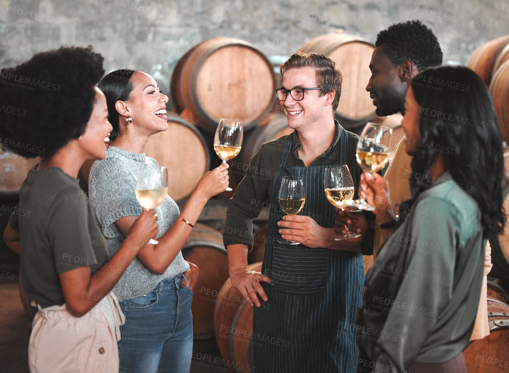 Buy stock photo Group of friends wine tasting at a distillery or cellar drinking glasses and enjoying the tour together. Happy, carefree and diverse people bonding and having fun at a winery estate