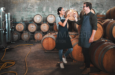 Buy stock photo Wine distillery owners cheers glasses in the cellar standing by the barrels. Happy and celebrating business owners or sommeliers enjoying chardonnay or sauvignon blanc inside a winery