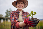 Gardner or farmer passionate about sustainability and organic farming holding a small plant or seedling in her hands. Nature activist in protection of environment and happy about a sustainable farm