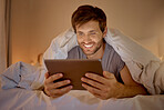 Happy man relaxing in bed with digital tablet watch, movie, series or online social media videos on an app. Browsing the internet news with 5g technology on wireless device in the bedroom at home