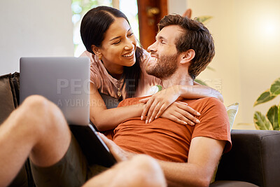 Buy stock photo Happy couple bonding and streaming on laptop while relaxing on couch at home, talking and laughing. Interracial husband and wife enjoying their relationship, embracing and watching a movie together