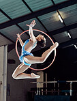 Sports woman, performance and ring in the air for gymnastics show. Fitness girl doing artistic pose and stretch for acrobat stunt. Young and beautiful athlete in gym with hula hoop and flexible body.
