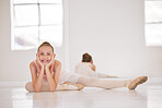 Portrait of happy ballet dancer on a break from training in a dance studio, smiling and stretching. Excited, flexible girl resting on a floor while doing warm up exercise before a rehearsal routine