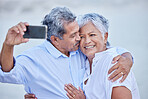 Love, senior couple taking phone selfie and smile, happy together and kiss for picture or video. Man and woman living retirement lifestyle take photograph with digital smartphone on romantic date

