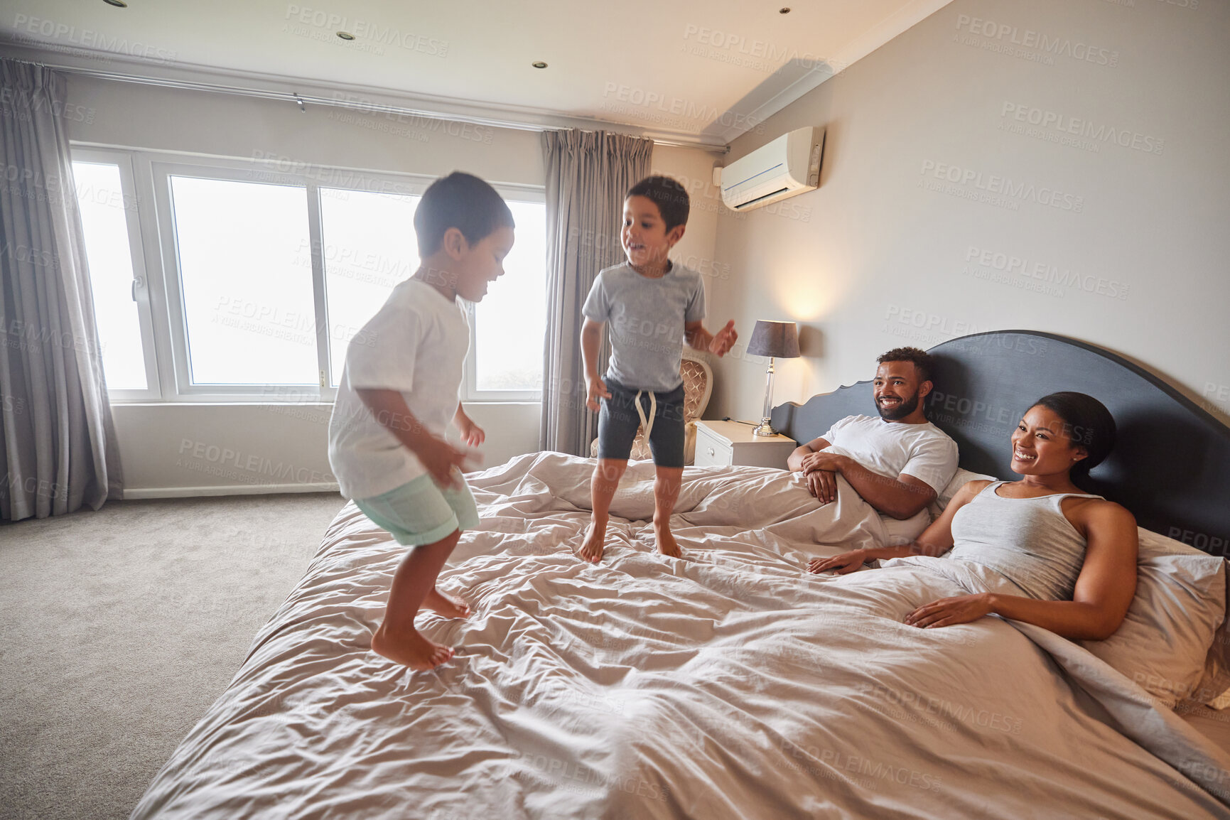 Buy stock photo Mother, father and children jump on bed or bedroom and wake up happy together in family home in the morning. Happiness, love and smile of kids with parents in a house for real estate or holiday