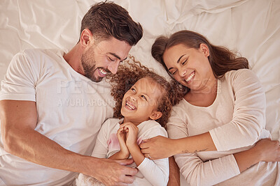 Buy stock photo Happy family playing and laughing together on the bed having fun at home on a weekend. Playful and carefree parents, mother and father bonding with their daughter, child or kid in the bedroom