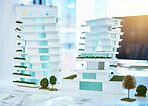 Building real estate model on a table in an architecture or construction business office. Creative 3d apartment or hotel design on a planning desk with blueprint paper in realtor company desk
