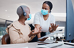 Manager consulting a call center agent about business paperwork with face masks during a pandemic. Black, young and customer support worker discussing a work mistake with her mentor in an office.
