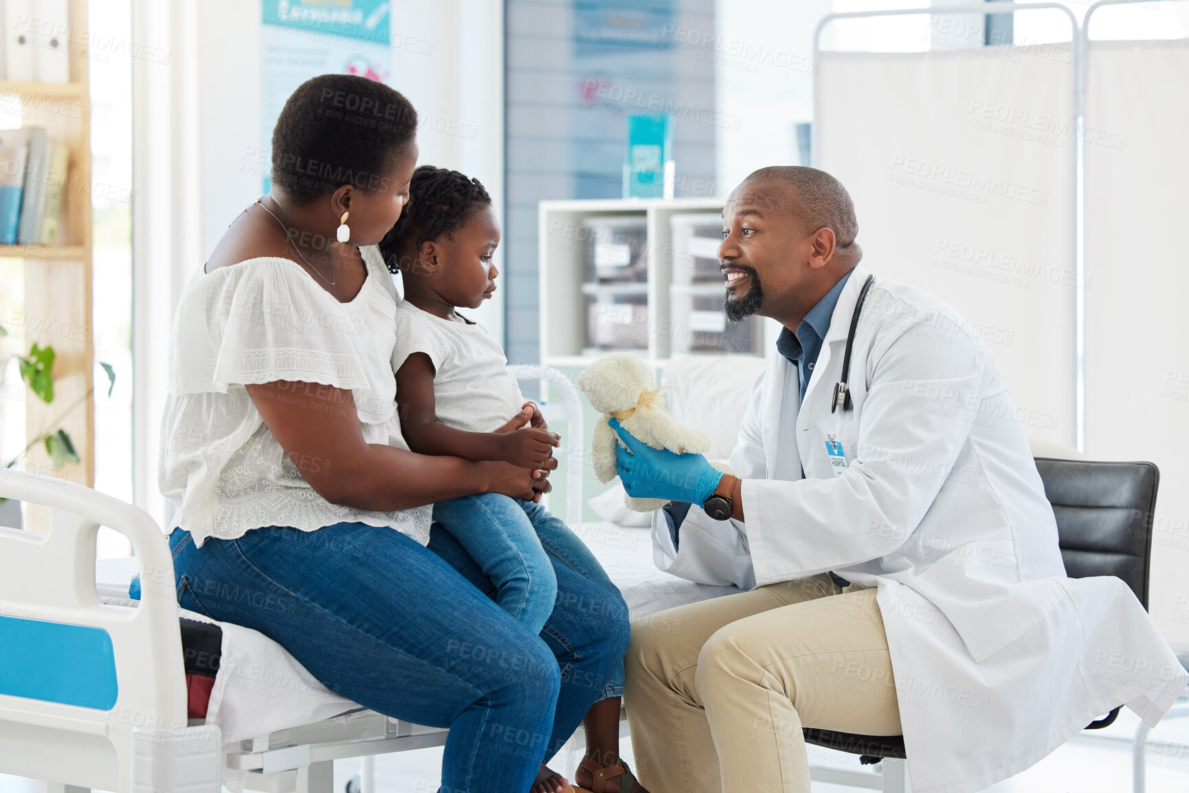 Buy stock photo Doctor or pediatrician gives a teddy bear to a little girl after a medical appointment in a clinic with her mother. Small, happy child visiting the specialist for checkup in a healthcare hospital 
