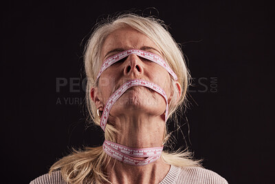 Buy stock photo Anorexia, tape measure and face of woman with eating disorder in studio on a dark background. Mental health, bulimia and depression of mature female with facial measuring tape and weight loss problem