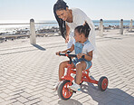 Summer, ocean and mother with girl on bicycle enjoying holiday, vacation and quality time together on weekend. Family, love and mom with young child on bike for support, freedom and adventure by sea