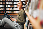 Student, library and smile for reading books in learning, education or knowledge at university. Happy woman smiling enjoying book read, story or study in research for assignment or project at campus