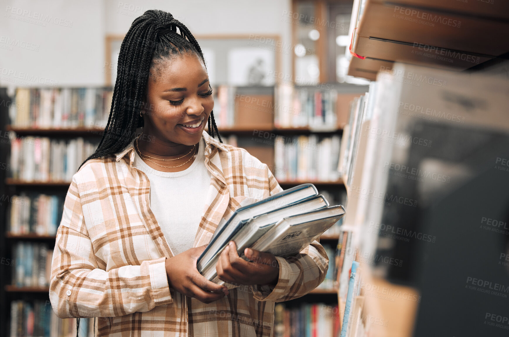 Buy stock photo Black woman, university student and library with books for education, learning and knowledge at campus. Happy, smile and gen z college student at bookshelf for studying, academic research and reading