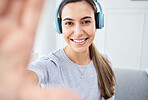 Portrait of happy woman take selfie and smile with headphones while listening to music in the living room. Young beautiful lady streaming a podcast at home and relax in lounge and express happiness