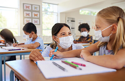 Buy stock photo Covid, education and learning with a teacher helping a student during class at school with classmates in the background. Female educator wearing a mask and assisting a girl child with her study work