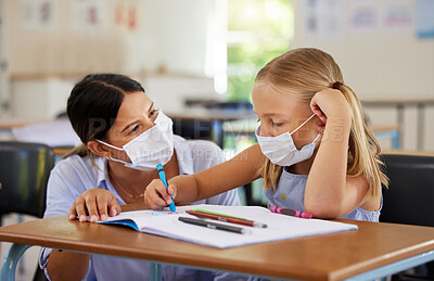 Buy stock photo Education, covid and learning with face mask on girl doing school work in classroom, teacher helping student while writing in class. Elementary child wearing protection to stop the spread of a virus