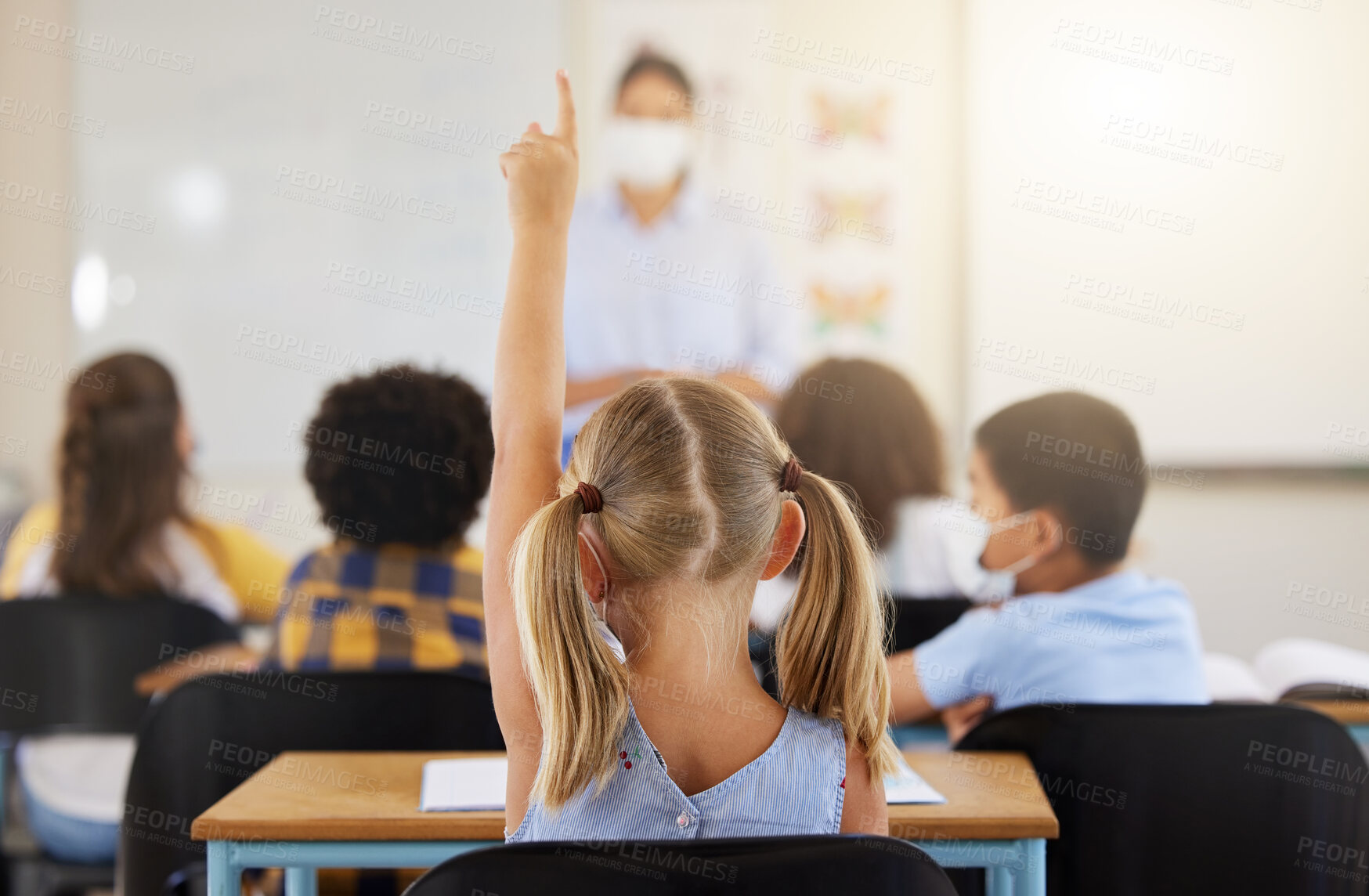 Buy stock photo Learning, smart and little girl in class holding up a hand to answer a question at school. Back view of a young student sitting at a classroom desk looking to solve the questions a teacher is asking