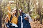 Selfie, happy couple and hiking adventure while holding phone for vacation travel memories in a forest or woods. Happy, love and exercise in healthy relationship with black man and white woman