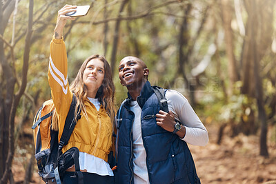 Buy stock photo Selfie, happy couple and hiking adventure while holding phone for vacation travel memories in a forest or woods. Happy, love and exercise in healthy relationship with black man and white woman