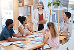 Female leadership, teamwork and planning during a meeting to explain business strategy, vision and mission at table with team diversity. Group of employees listen to boss talk about financial report