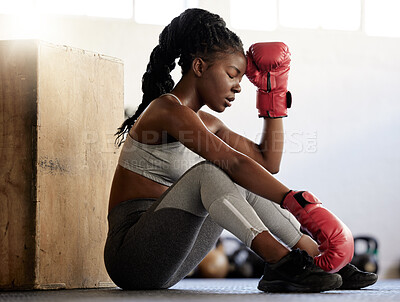 Buy stock photo Sport, fitness and woman boxer on break from exercise and training on the floor of a gym. Black athlete looking exhausted with low energy during a routine workout. Female resting after physical match