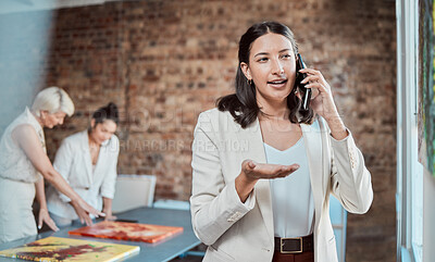Buy stock photo Painting, artistic and call with a woman art gallery manager talking on a phone in a studio with her team in the background. Paint, creative and collaboration with a team selling artwork in an office
