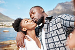 Couple kiss in a selfie at the beach in summer to post it on social media on a sunny day in nature together. Travel, love and black woman kissing her African boyfriend in an ocean portrait on holiday