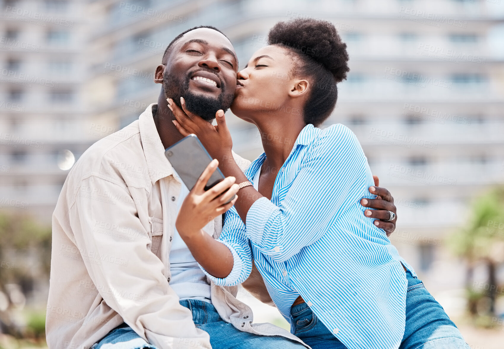 Buy stock photo Love, kiss and couple take phone selfie on romantic date together, happy and smile while relax outdoors on summer holiday. Black woman and man on a romance travel adventure or journey in urban city