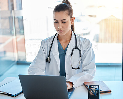 Buy stock photo Doctor typing on a laptop in an office writing a proposal or on a video call using telemedicine. Young healthcare professional or GP using the internet for research or online consultation