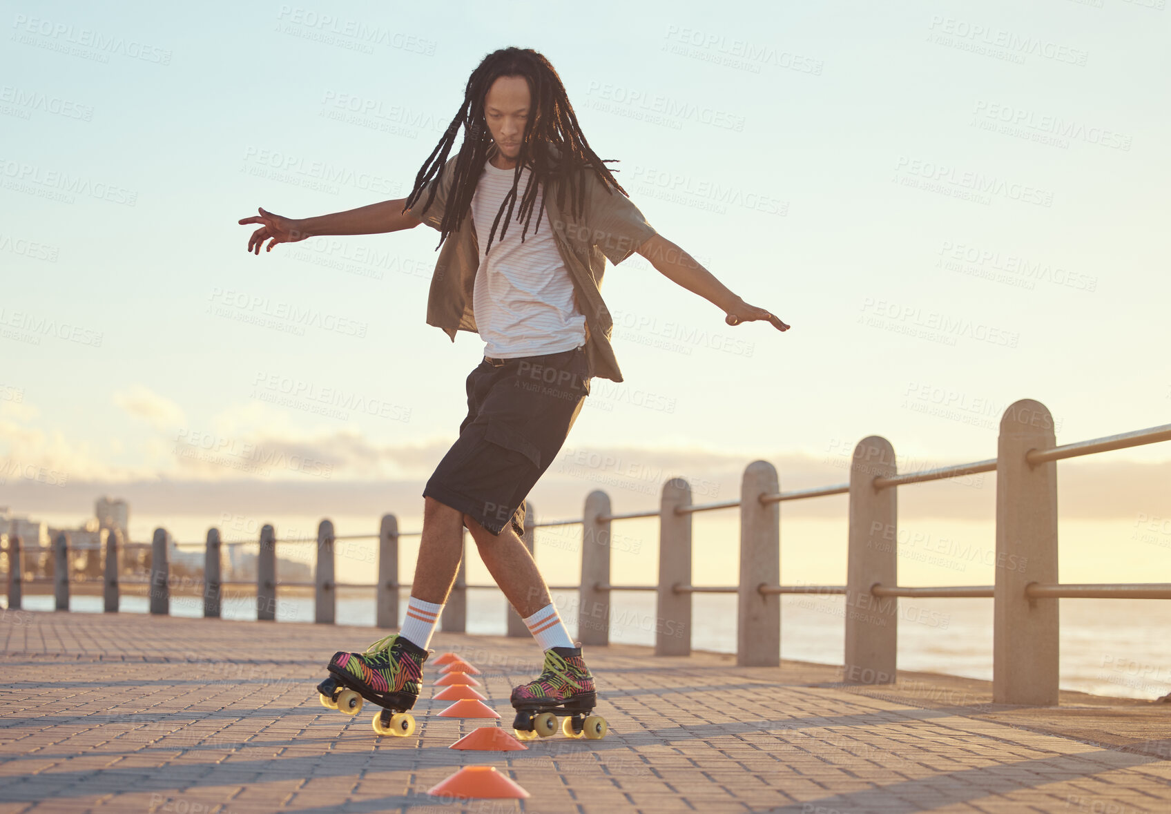 Buy stock photo Roller skates, beach and sport with a man riding around training cone for fun, fitness and exercise at the seaside promenade. Hipster male athlete skating outside for leisure, health and recreation