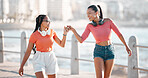 Walking, fist bump and happy friends on walk while calm, relax and at peace in new city or town. Partnership, support and team of girl best friends bond while they travel down a ocean or sea sidewalk
