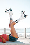 Fun, roller skates and beach vacation in summer with woman enjoying hobby, relax and freedom while skating. Legs and shoes of a female skater being fit and active while at sea for leisure and travel