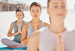 Women friends meditation while training yoga exercise on the beach. Young zen spiritual female athlete workout outdoor. Faith, inner peace, balance and getting healthy focus on a fitness lifestyle