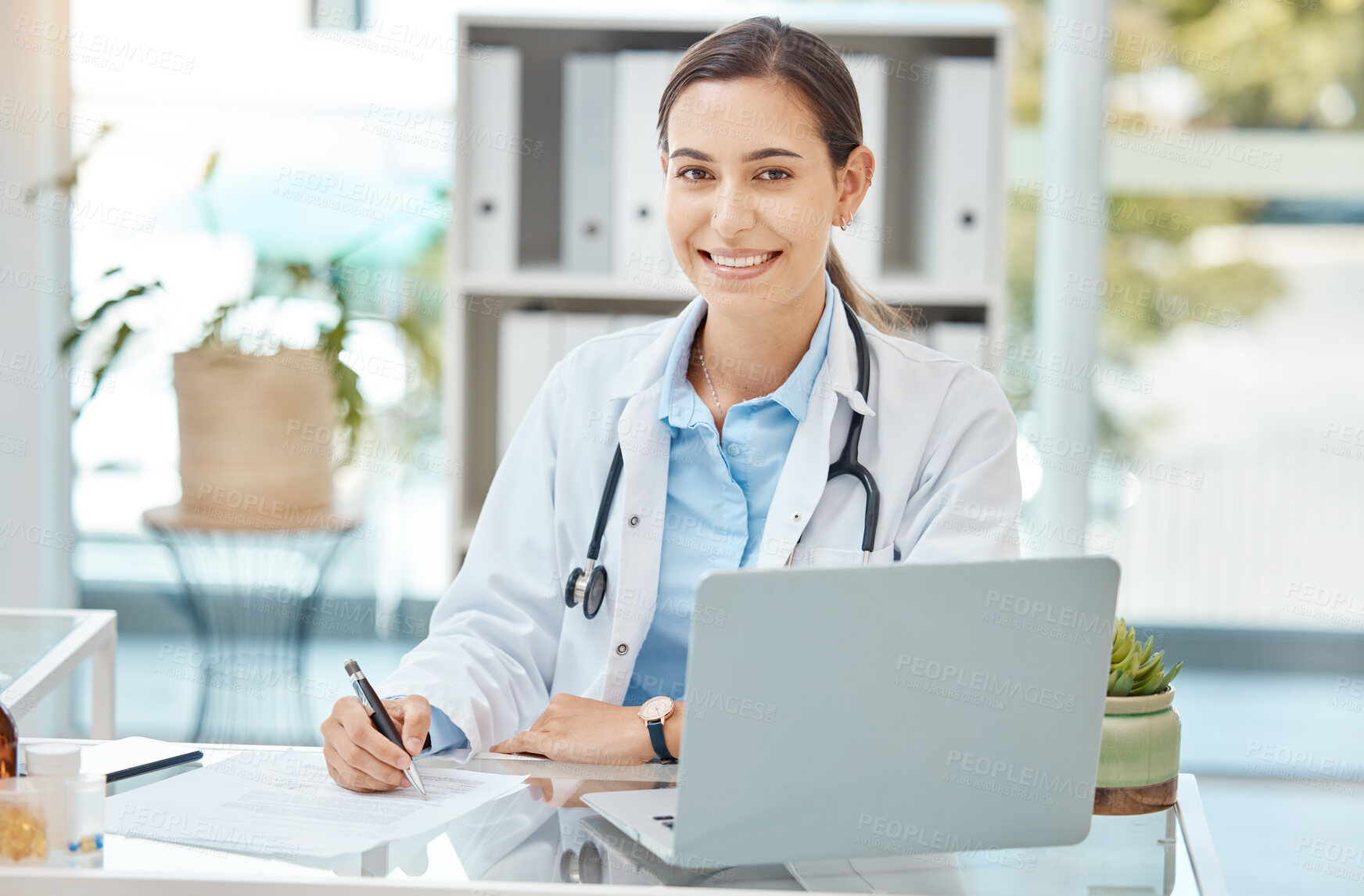 Buy stock photo Healthcare, medicine and a doctor writing on insurance document or patient file. Happy woman working in medical field, at desk with laptop consulting online and filling in a script at hospital office