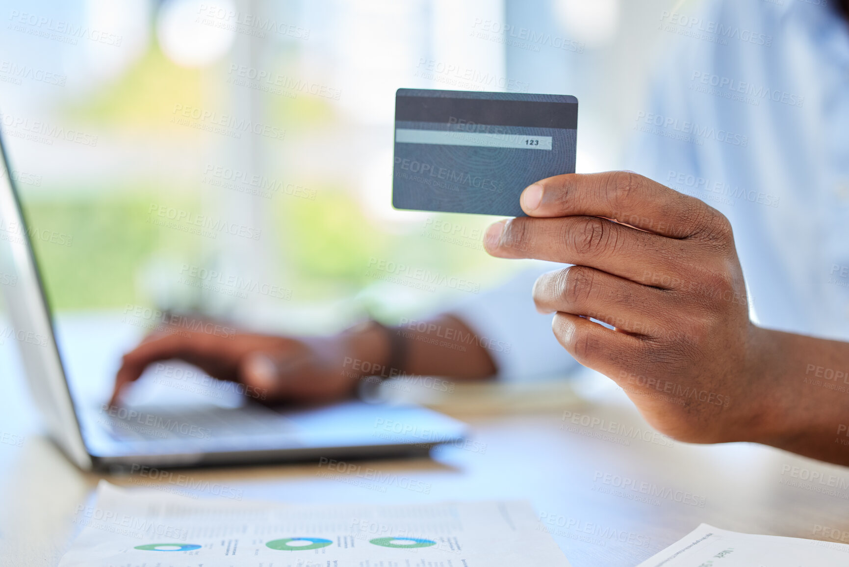 Buy stock photo Man has credit card in hand, for online shopping or payment of bills via app on his laptop. Male customer at table has card for banking information, to pay on ecommerce store or website on computer.