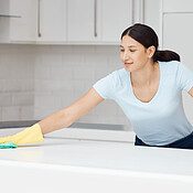 Cleaner woman cleaning kitchen counter with cloth, spray bottle and rubber  gloves in modern home in Stock Photo by YuriArcursPeopleimages