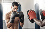 Boxing gym, fighting pad and man training with athlete coach for a fitness cardio exercise session. Strength, focus and fighter workout for punch technique with professional sports equipment.