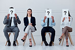 Job interview, question mark and feedback with business people sitting with sign for review, recruitment and search. Why, faq and hiring with employees holding icon for opinion, vote or policy