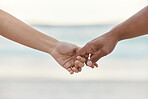 Touch, love and support with interracial couple holding hands in a committed, loving and close relationship. Closeup hands of man and woman enjoying beach travel, sea vacation or holiday and romance