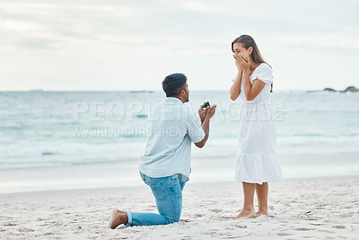Buy stock photo Love, couple and beach engagement proposal for marriage, partnership and commitment on ocean sea sand. Wow, shocked and surprised woman with romantic man on one knee presenting a union wedding ring
