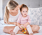 Portrait of girl with mother in bedroom in home, bonding and playing while holding toy. Love, family and caring happy woman with little kid, child or toddler spending free time together in the house
