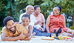 Portrait of a black father and child at a picnic with family in an outdoor green garden during spring. Smile, happy and african people eating healthy fruit at a outside celebration in a park.