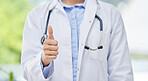 Doctor, thumbs up and hand of a medical professional in thank you healthcare gesture against blurred background. Hands of a expert surgeon with stethoscope in yes sign or agreement for health success