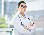 Portrait of a doctor with arms crossed in her consultation office with glasses and a stethoscope. Woman healthcare professional standing in a room in a medicare hospital, clinic or surgery center.