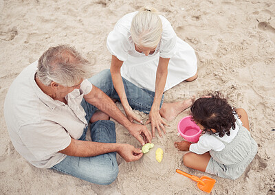Buy stock photo Family, beach and play with grandparents and child building sand castle together for vacation, fun and relax. Summer, happy and retirement couple with young girl playing by the sea for holiday break
