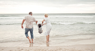 Buy stock photo Family, children and beach with a girl and her grandparents by the sea or ocean in nature. Sand, water and summer with a senior man, woman and their granddaughter on holiday or vacation by the coast