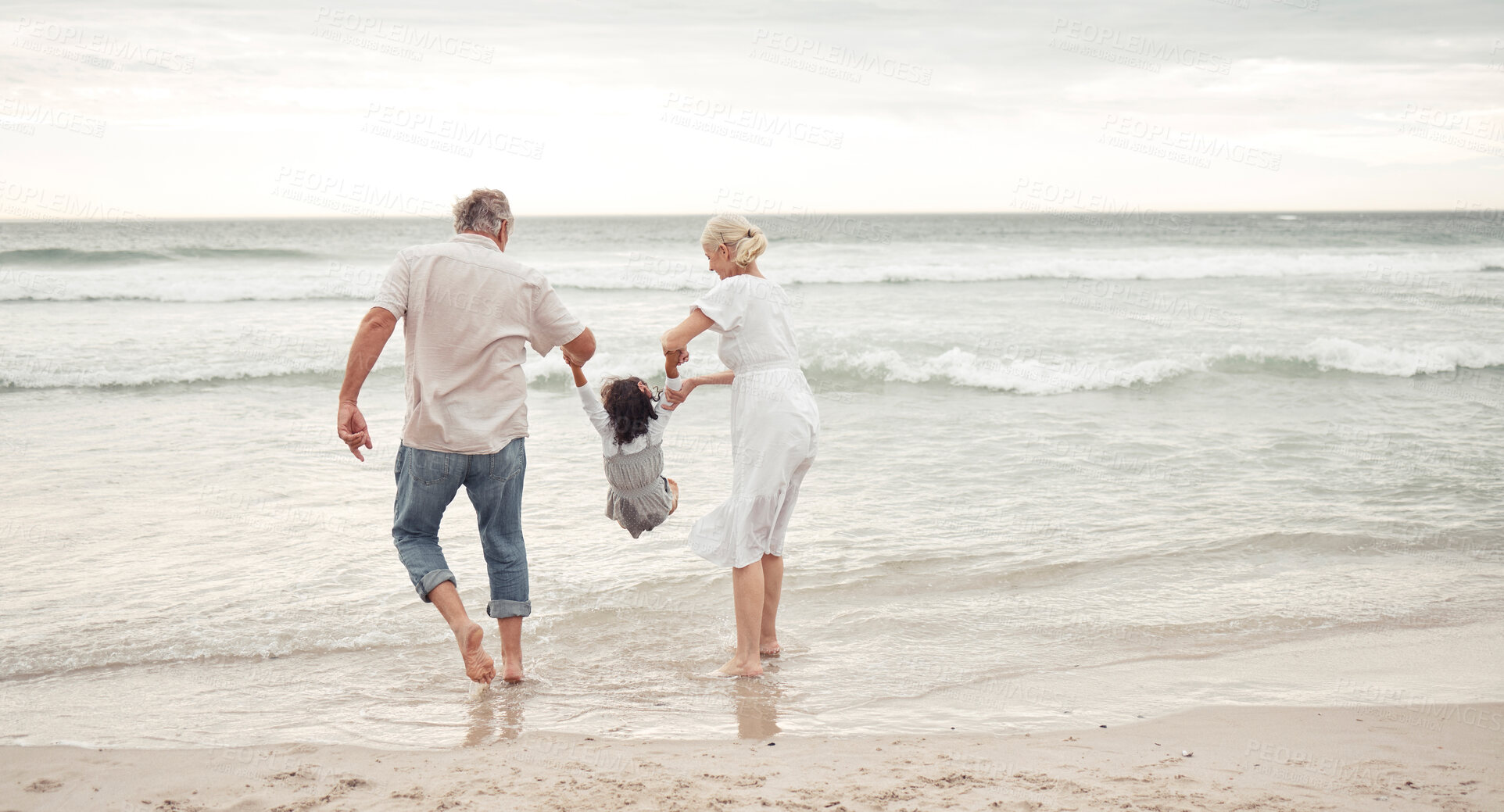 Buy stock photo Family, children and beach with a girl and her grandparents by the sea or ocean in nature. Sand, water and summer with a senior man, woman and their granddaughter on holiday or vacation by the coast