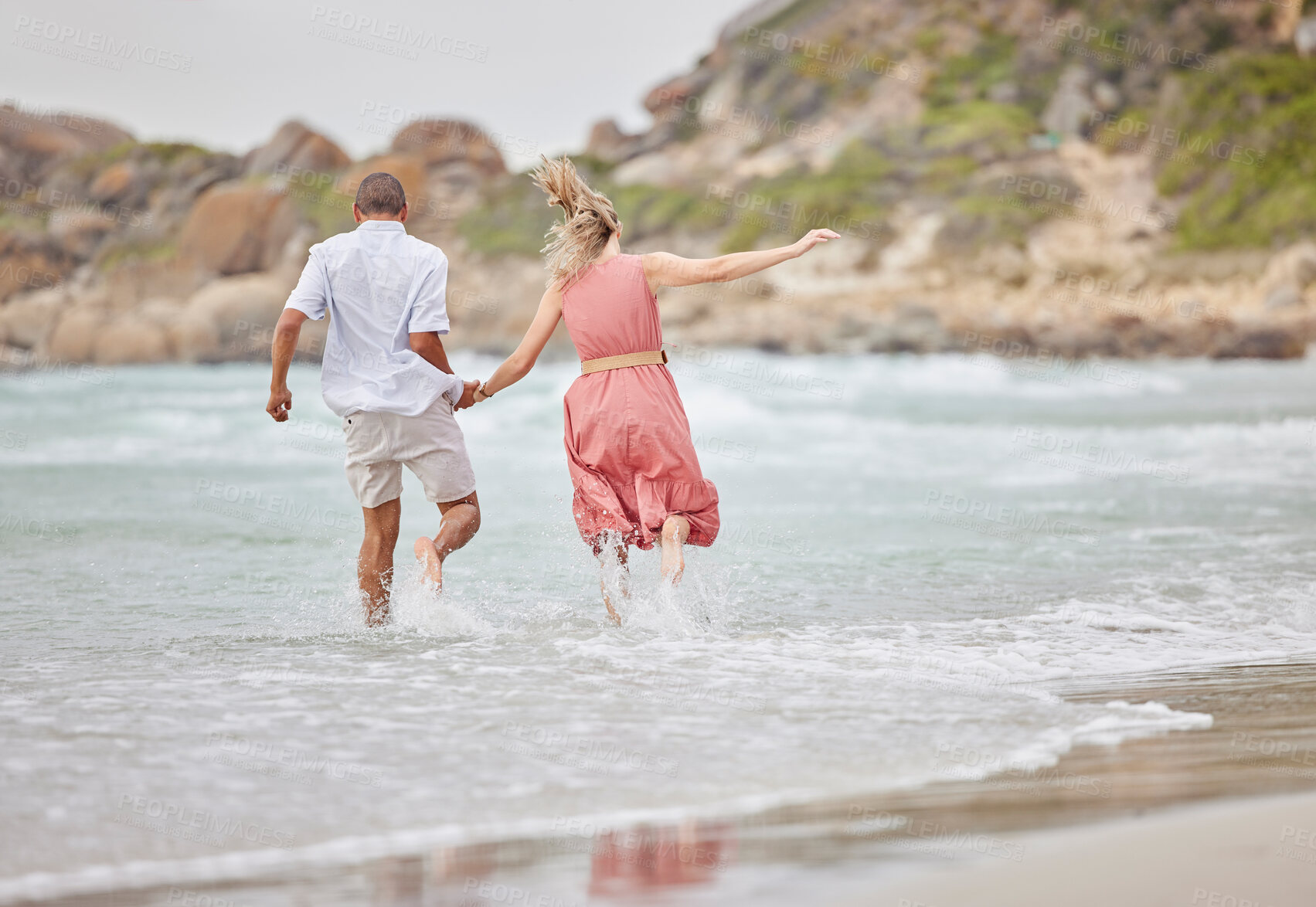 Buy stock photo Interracial couple, ocean fun and holiday vacation together holding hands and enjoying the water. Man and woman bonding in a joyful relationship for beach time, waves and nature in the outdoors