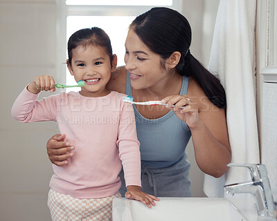 Buy stock photo Children, dental and toothbrush with a girl and her mother brushing their teeth together in the bathroom of their home. Family, hygiene and oral with a woman and daughter practicing care and hygiene