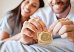 Condom, safe and sex with the hands of a man opening protection for sexual intercourse in bed with a partner. Happy, love and couple with a woman and her boyfriend using contraceptive in the bedroom